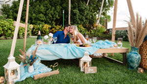A Caucasian couple sitting at an outdoor dinner on the grass.
