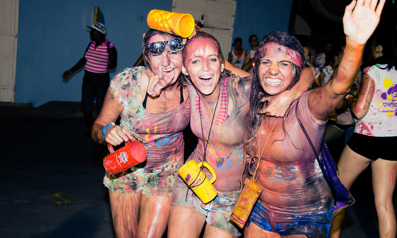 Three girls at Foreday Morning J'ouvert in Barbados in the Summer. Covered in paint and excitedly smiling at the camera.